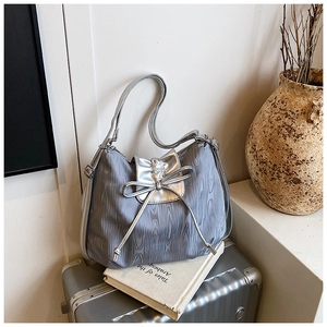 Detail of grey textured fabric tote bag with silver bow on vintage travel luggage