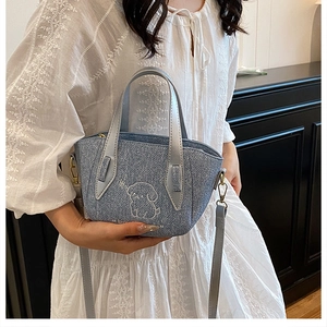 Close-up of light blue denim mini bag featuring detailed white puppy embroidery