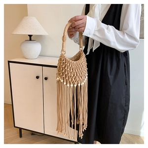 Detail of bohemian hand-woven bag featuring long tassels and decorative white beads