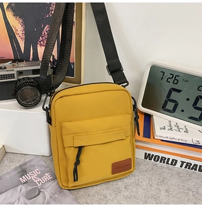 Detail of yellow canvas crossbody bag featuring functional pocket and adjustable nylon strap