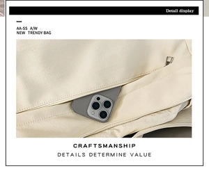 Macro detail of the side zipper pocket on a cream pleated shoulder bag with a smartphone