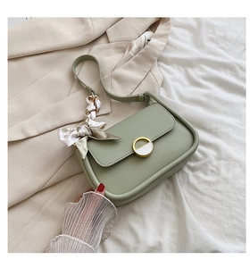Détail du sac selle vert clair avec boucle métallique et foulard élégant en soie