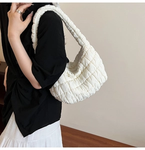 Detail view of a white quilted cloud bag featuring soft pleated shoulder strap texture