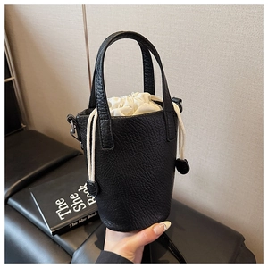 Detail of black lychee grain leather mini bucket bag with a white fabric drawstring lining
