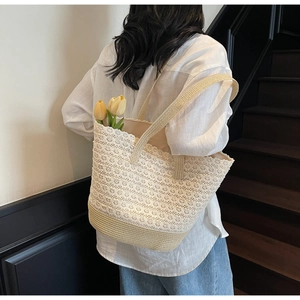 Détail d'un sac cabas en dentelle beige et paille avec doublure florale interne