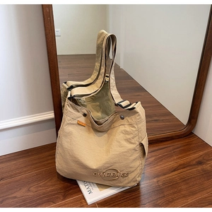 Dettaglio di una borsa tote grande beige in tela con tracolla regolabile e ricamo di marca