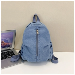 Détail du sac à dos en denim bleu avec fermeture éclair verticale et poches pour ordinateur