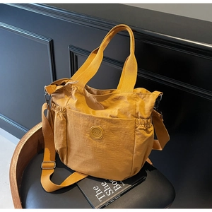 Detail of yellow nylon tote bag featuring side pockets and adjustable shoulder strap