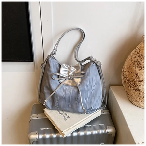 Detail of silver tote bag with wood grain texture and metallic bow accent