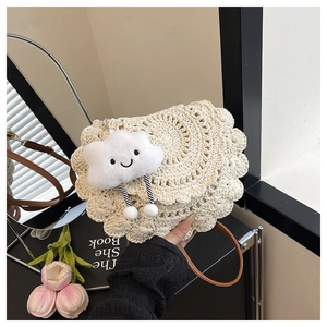 Detail of hand-woven beige saddle bag with wavy scalloped edges and a cute cloud charm