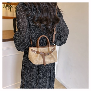 Detail of beige woven texture beach bag with brown faux leather trim and strap