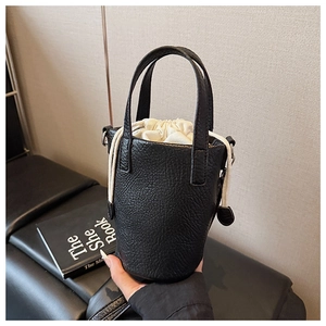 Detail of black lychee grain leather bucket bag with white drawstring lining and neat stitching