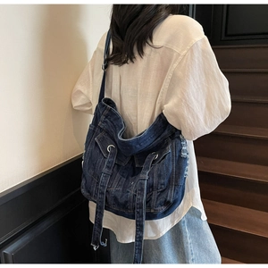 Detail of blue denim crossbody bag featuring vintage jacket-style pockets and stitching