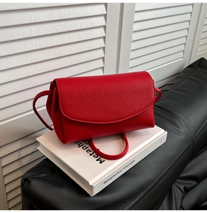 Détail du cuir grainé rouge sur un petit sac à bandoulière moderne avec rabat