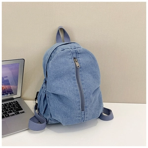 Détail du sac à dos en denim bleu montrant la fermeture éclair et les poches latérales