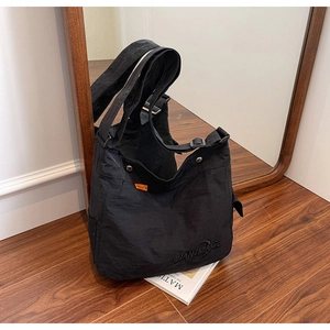 Dettaglio macro della borsa tote in nylon nero con logo a sbalzo e etichetta arancione
