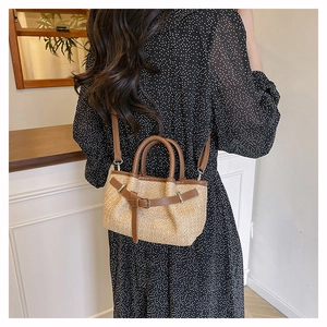 Detail of straw woven texture and brown leather strap on minimalist crossbody beach bag