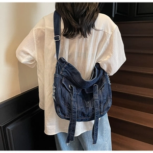 Detail of vintage blue denim hobo bag featuring retro washed texture and unique jacket style pockets