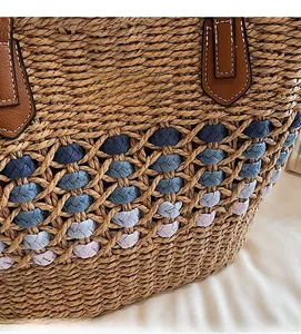 Détail du tissage en paille et de la poignée en cuir marron avec surpiqûres blanches