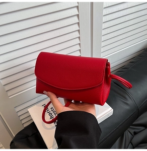 Gros plan sur le rabat en cuir rouge à motif litchi et la texture d'un petit sac carré