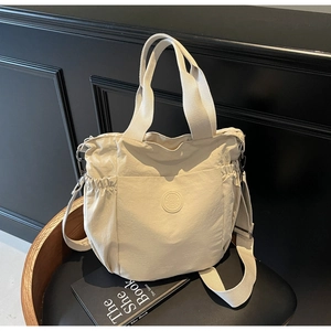 Detail of off-white canvas tote bag with drawstring pockets and adjustable strap