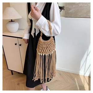 Detail of bohemian handmade crochet bag featuring white beads and long fringe tassels