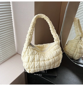 Close-up of quilted puff cloud bag in pale yellow with silver zipper and textured handle
