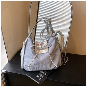 Detail of silver-grey tote bag with wood texture pattern and stylish leather bow