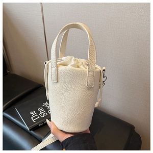 Detailed macro view of beige bucket bag showing lychee pattern leather and drawstring liner