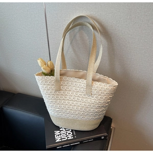 Détail montrant des couches de crochet floral en dentelle crème sur un sac cabas tissé
