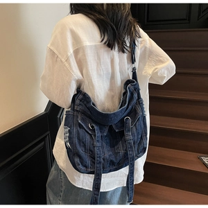 Detail of vintage blue denim crossbody bag featuring workwear style and metal buckle