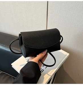 Gros plan détaillé du cuir de vachette noir grainé et de la fine bandoulière du sac