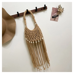 Detail of handmade macrame tote bag with long bohemian tassels and decorative white beads