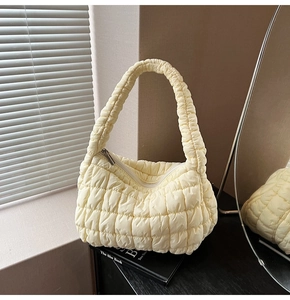 Close-up of yellow quilted puffy cloud bag with soft textured fabric and metal zipper