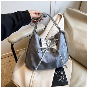 Detail of silver-grey tote bag with metallic bow and wood-grain textured fabric
