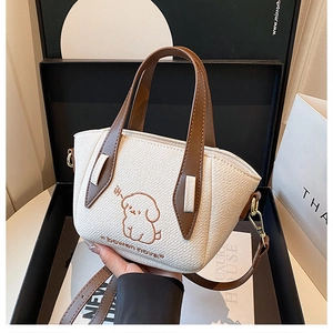 Close-up of a white canvas handbag with brown leather handles and puppy embroidery