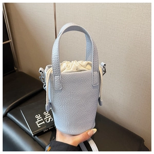Close-up of light blue pebbled leather bucket bag with white drawstring inner pouch