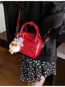 Elegant red patent leather top handle bag with plush charm and crossbody strap
