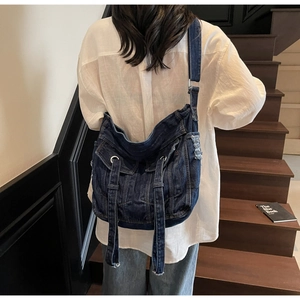 Detail of vintage blue denim crossbody bag featuring utility pockets and adjustable strap