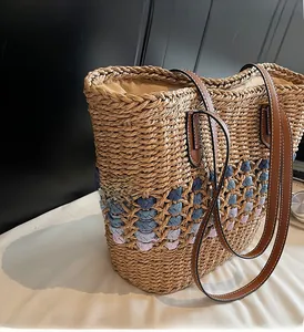 Détail du sac cabas en paille avec motifs géométriques bleus et anses en cuir marron