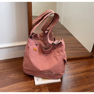 Dettaglio borsa tote rosa antico con tracolla regolabile e tasca su pavimento in legno