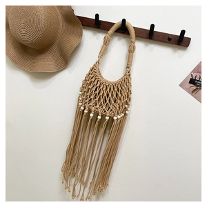 Macro view of beige Bohemian crochet bag with delicate beads and long fringes