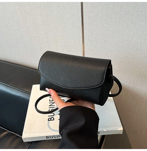 Détail du sac bandoulière noir en cuir texturé avec rabat minimaliste et coutures précises