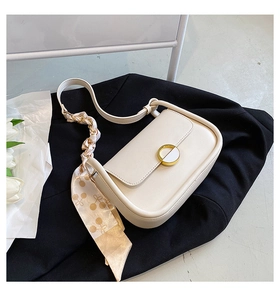 Détail du sac de selle blanc cassé avec boucle dorée et foulard en soie motif cerise