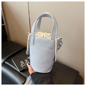 Detail of light blue bucket bag with lychee grain leather and drawstring closure