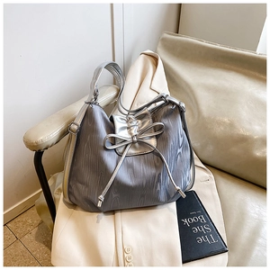 Detailed view of silver-grey tote featuring a large bow and textured fabric on a chair
