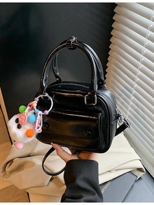 Glossy black pillow handbag with plush keychain charm and crossbody strap for women