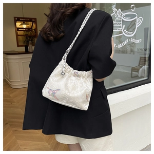 Detail of floral embroidery and butterfly motif on textured canvas shoulder bag