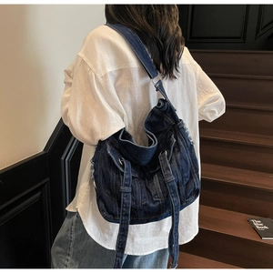 Detail of vintage washed blue denim hobo bag featuring frayed edges and silver hardware