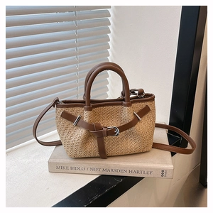 Detail of woven straw mini tote featuring brown leather trim and silver metal buckle